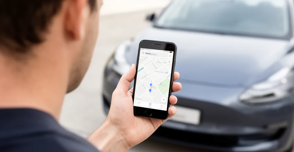 Ondernemer gebruikt telefoon voor navigatie naast auto